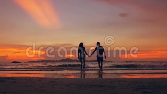 慢动作剪影快乐相爱的情侣亲吻在海边的夕阳下去海滩视频的预览图