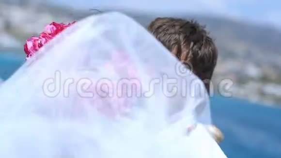 新婚夫妇拥抱在海和山的背景上视频的预览图