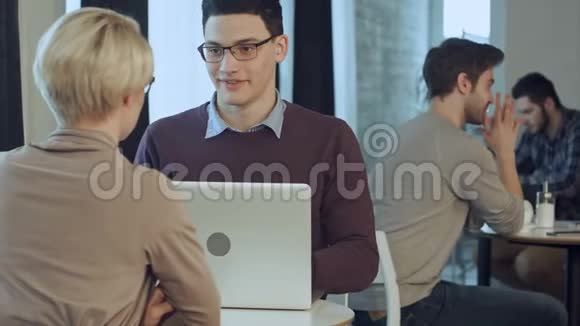 两个年轻的商人在现代办公大厅使用笔记本电脑视频的预览图