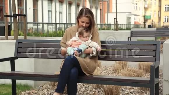 年轻的母亲和孩子坐在长凳上视频的预览图