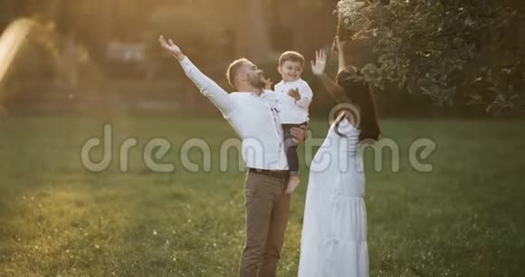 幼儿家庭家长与幼儿儿子玩耍快乐的爸爸妈妈抱着宝宝在户外微笑视频的预览图