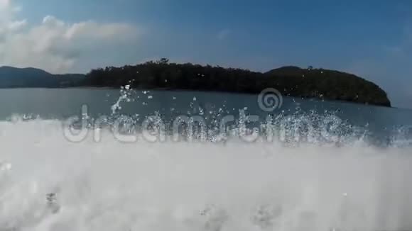 泡沫水流喷溅船漂浮在热带岛屿附近视频的预览图