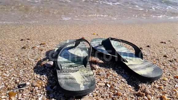 拖鞋站在海边黑色的拖鞋站在海滩上视频的预览图