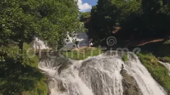 空中观景两位音乐家Pianist和bandura在瀑布的岩石上演奏视频的预览图