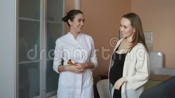 一位女医生和一位年轻的孕妇正站在办公室里谈论母性视频的预览图