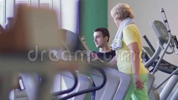 老年妇女在健身房跑步机上行走视频的预览图