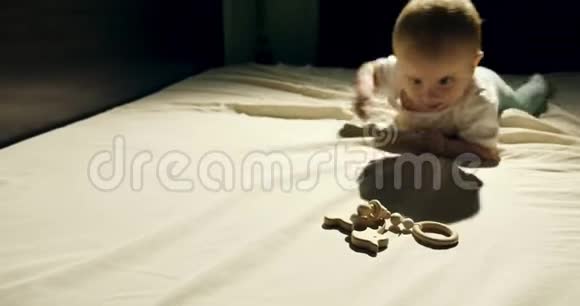 可爱的好奇宝宝在床上玩木玩具小宝宝晚上在玩木玩具视频的预览图