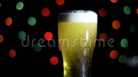 黑色背景上的一杯冷啤酒有彩灯啤酒在玻璃杯里起泡视频的预览图