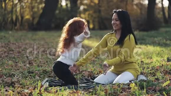 可爱的小女孩在秋天公园拥抱她的母亲幸福家庭概念视频的预览图