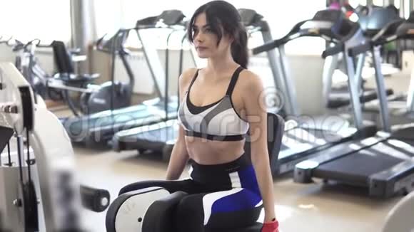 运动女运动员在运动室的模拟器上做臀部和股骨后部的运动视频的预览图