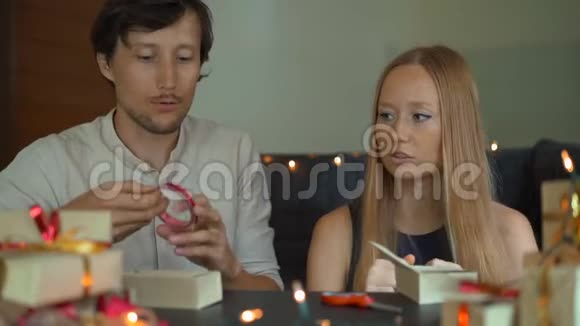 一个年轻女人和男人的慢镜头爸爸和妈妈包礼物用红色和红色的纸包裹的礼物视频的预览图