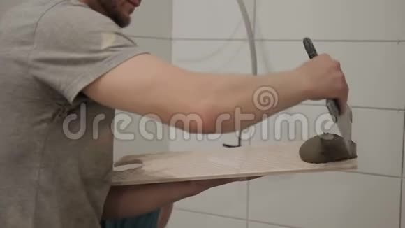 一个人用一个铲子把一块瓷砖覆盖在墙上穿工作服的人蹲着视频的预览图