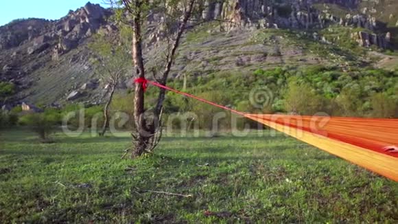 女旅行者在山景的橙色吊床上休息视频的预览图