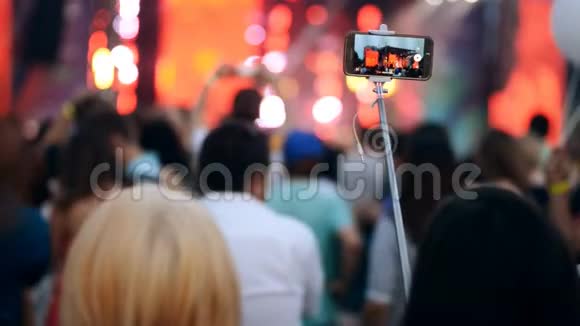 人群中的女人在她的智能手机上制作露天音乐音乐会的视频视频的预览图