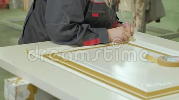在一家工厂一名妇女用一条保护胶带把室内木门的生产贴在门上视频的预览图