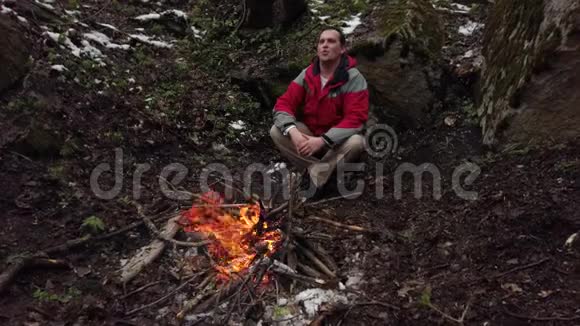 中年人坐在森林里的炉火旁视频的预览图
