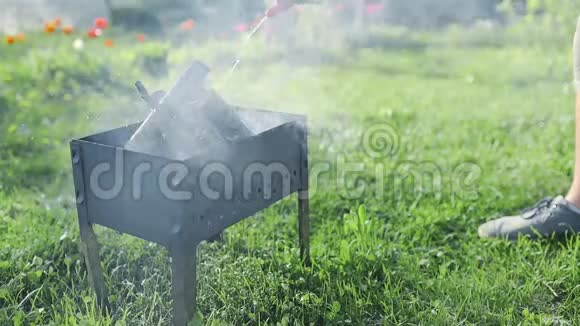 男人在烤架里的小烟木上加入液体点火火焰爆发在后院烧烤使人热视频的预览图