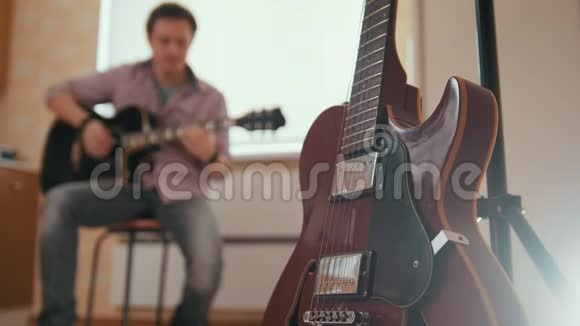 年轻有魅力的男人用吉他和戏剧作曲其他乐器在前景模糊的概念视频的预览图
