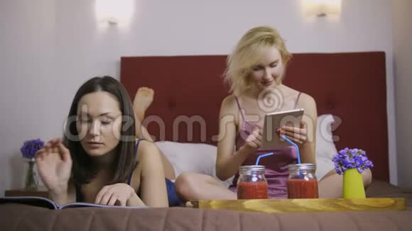 快乐的女性朋友在家里的床上玩视频的预览图