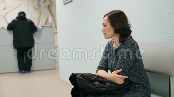 诊所里有个女人坐着等轮到她看医生视频的预览图