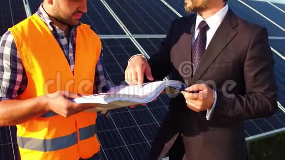 在镜头上工程师和商人讨论技术图纸太阳能电池板后面视频的预览图