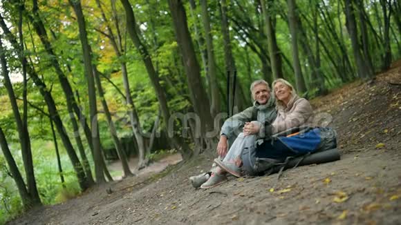 一对退休的游客在树林里休息视频的预览图