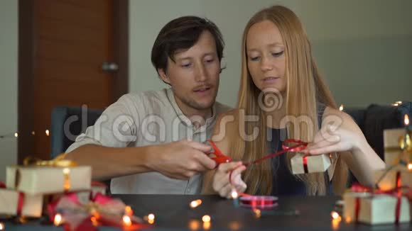 一个年轻女人和男人的慢镜头爸爸和妈妈包礼物用红色和红色的纸包裹的礼物视频的预览图