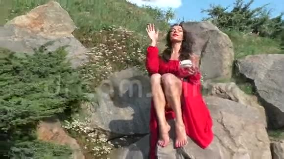 穿红色裙子的女人坐在岩石上视频的预览图