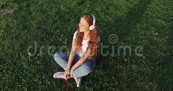 年轻快乐的女人红色卷发享受音乐视频的预览图
