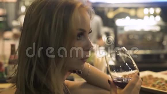 年轻女子在餐馆里喝着酒杯里的红酒女士在品酒时喝着酒杯里的红酒视频的预览图