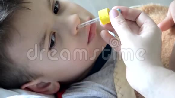 婴儿药和生病的孩子男孩躺在沙发上发烧休息在家里妈妈给她的儿子吃药视频的预览图