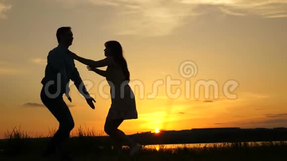 爱的男人和女人在湖底明亮的阳光下跳舞一对夫妇在海滩上日落时跳舞快乐视频的预览图