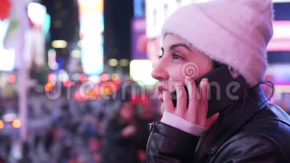 年轻女子晚上在时代广场打电话视频的预览图
