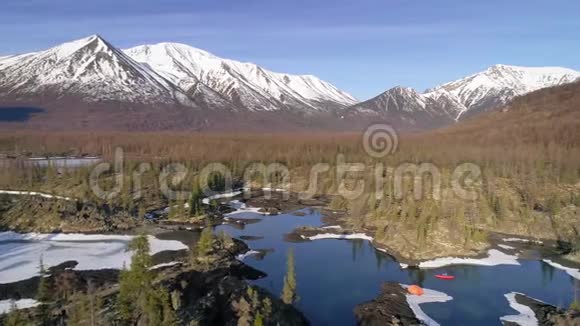 游客在湖边的独木舟上航行靠近山谷露营空中飞行视频的预览图