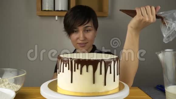 女厨师在厨房准备一个甜蛋糕把巧克力奶油倒在上面视频的预览图