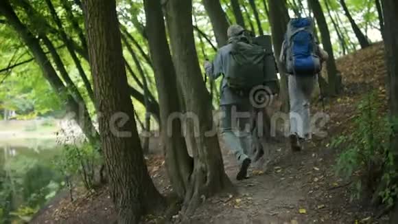 一对活跃的老年夫妇在森林中的路线后景视频的预览图