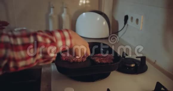 在煤气炉旁的特写镜头女人把汉堡从锅里翻出来视频的预览图