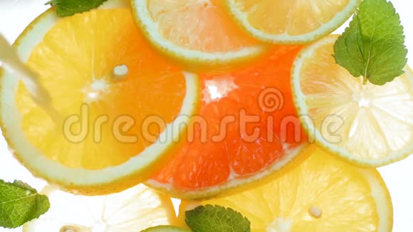 在装满柑橘类水果片和薄荷叶的罐子里倒入汁的特写慢动作视频视频的预览图