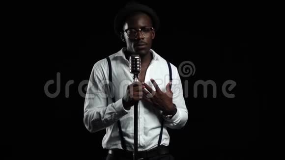 美国黑人男音乐家在录音室唱歌黑色背景慢动作视频的预览图