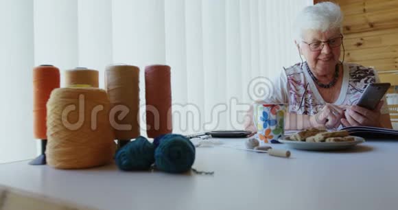 坐在桌子上操作手机的老妇人视频的预览图