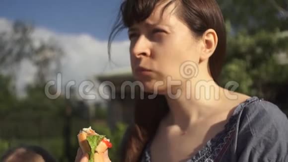 年轻迷人的女人吃户外热狗和番茄酱视频的预览图