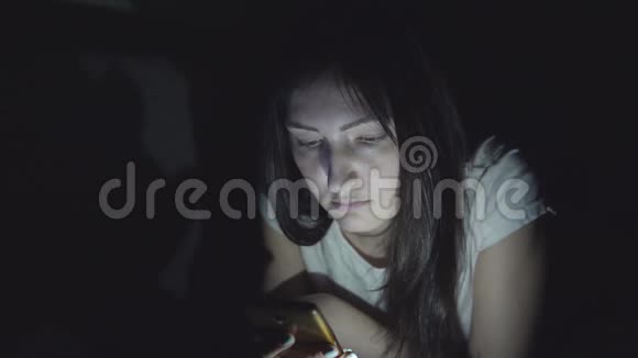夜深人静的年轻女子在社交网络中坐着一部手机视频的预览图