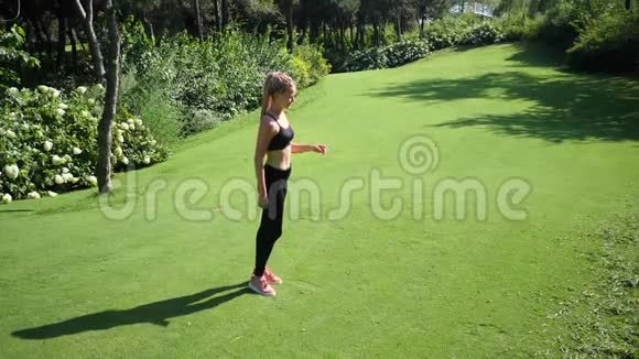 年轻的金发女子身材苗条在公共公园从事体操她在健身场所跑步视频的预览图