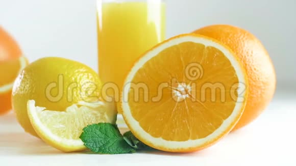 特写慢镜头视频镜头在白色木制的柑橘类水果和橙汁上翻拍视频的预览图
