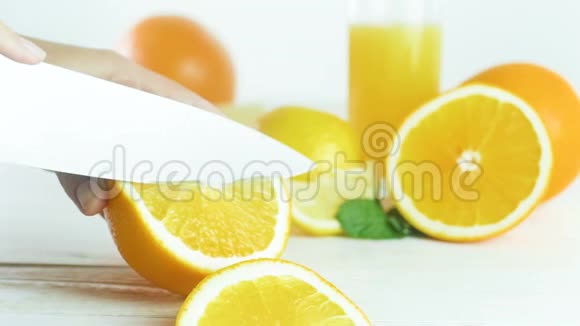 特写慢动作视频年轻的欧文在白色的木桌上切鲜多汁的橘子视频的预览图