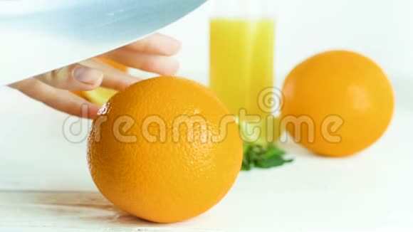 在白色的木桌上用大刀将橙色切成两半视频的预览图