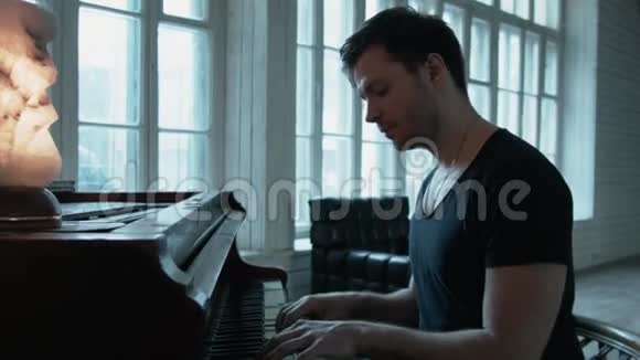 一个穿T恤的帅哥在对面的窗户上弹钢琴钢琴上有一盏红灯这就是视频的预览图