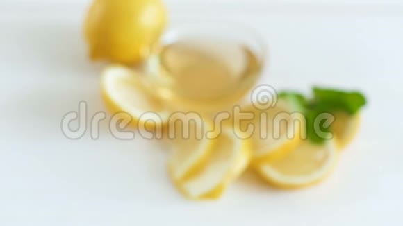 相机放大和聚焦柠檬与蜂蜜躺在白色木桌上视频的预览图