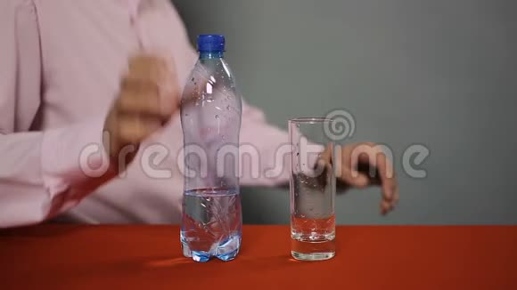 男人坐在咖啡馆里把瓶装的起泡矿泉水倒进玻璃里视频的预览图