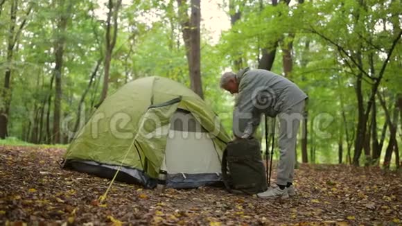漂亮的老人站在帐篷附近的森林里视频的预览图